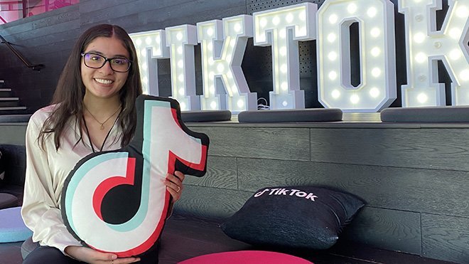 Tania Acosta sitting in front of a TikTok sign