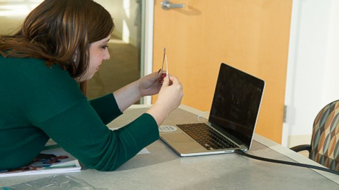 Student holds up wishbone to computer screen. 
