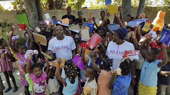 An alumnus poses with a group of schoolchildren in Haiti, where he brought supplies and disaster aid.