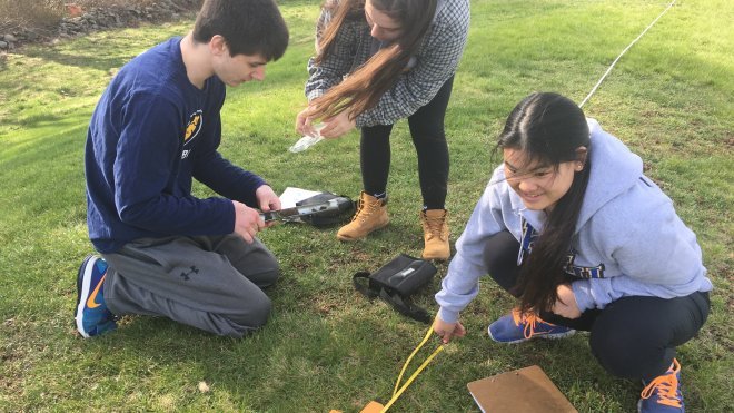 Three students conduct scientific field work.