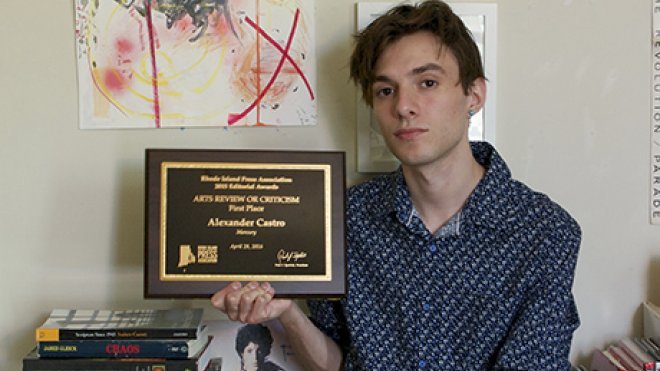 An alumnus holds his journalism award.