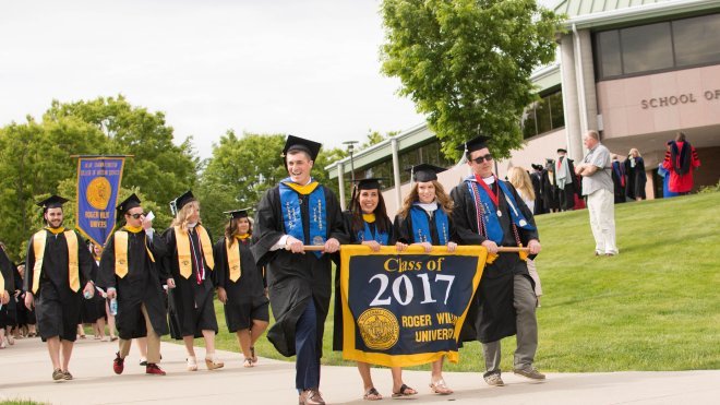 Graduates process to Commencement carrying the class banner.