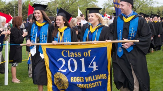 Graduates process with class banner
