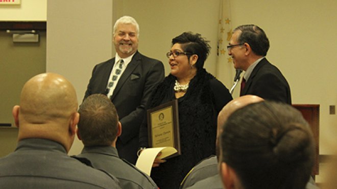 A woman and two men celebrate earning an award.