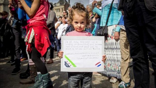 Refugee child holds up a book.