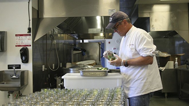 A worker finishes packaging a product inside an industrial kitchen.