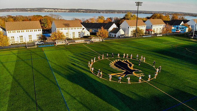 image of a group of RWU students encircle the Hawk logo on a playing field on the Bristol Campus