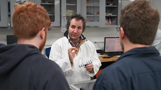 Ahmet Akosman speaks with students in the RWU laser lab.