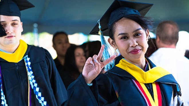 image of Meg Dela Dingco '19 flashing a peace sign at Commencement