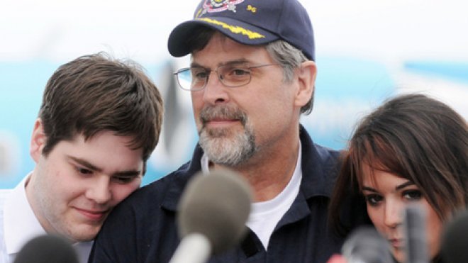 A man is surrounded by family at a press conference.