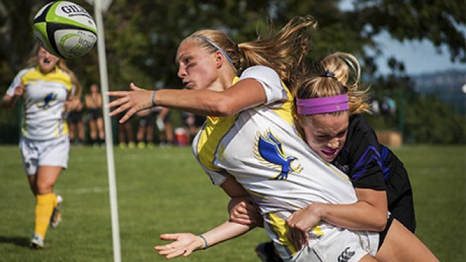 RWU rugby player passes to a teammate before she gets tackled by the opposing team.