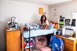Student on the top bunk in a dorm room