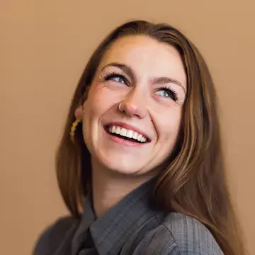 Smiling woman with long brown hair against a tan background