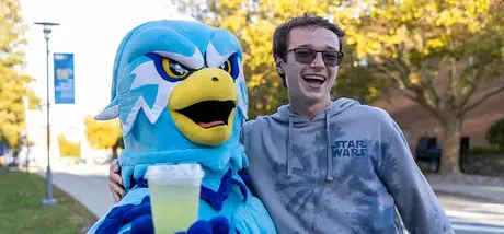 Student poses with RWU's mascot