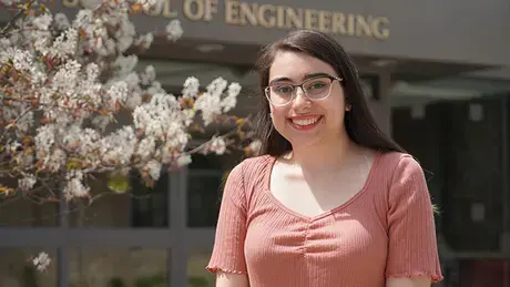 Cassidy Methot standing in front of the School of Engineering, Computing, and Construction Management.