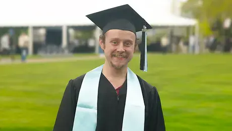 Thomas McDonough stands in his cap and gown at Commencement.