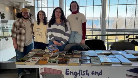 Students at the Book Nook Event standing behind a table of books