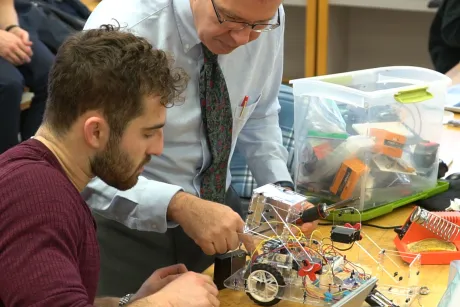 Engineering student repairs robot with help from Professor