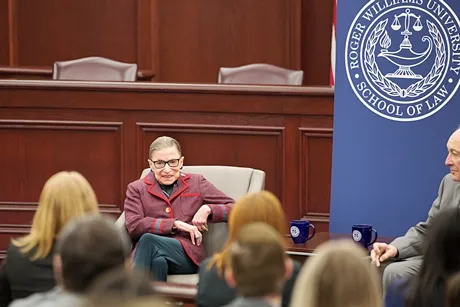 image of Supreme Court Justice Ruth Bader Ginsburg seated in a chair talking to students during her visit and 'fireside chat' at RWU Law in January 2018