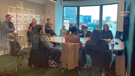 Students sit at a conference table with members from Goody Clancy Boston reviewing work