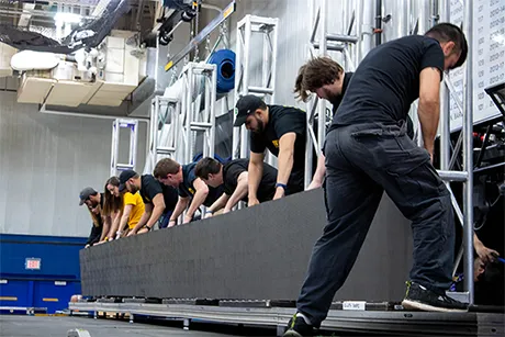Stage Crew members hooking up lighting display.
