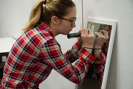 Student writes on a mirror.