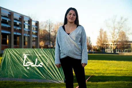 Student stands beside tent.