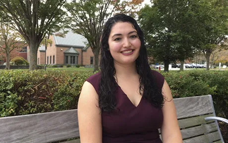 A student sitting on a bench on campus.