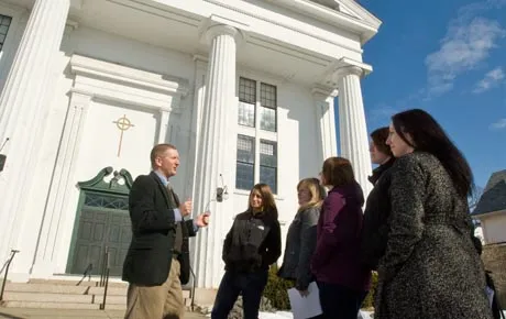 Professor lectures students on the steps of a historic building.