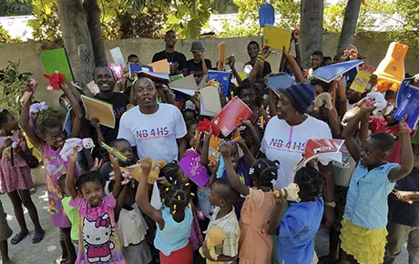 An alumnus poses with a group of schoolchildren in Haiti, where he brought supplies and disaster aid.