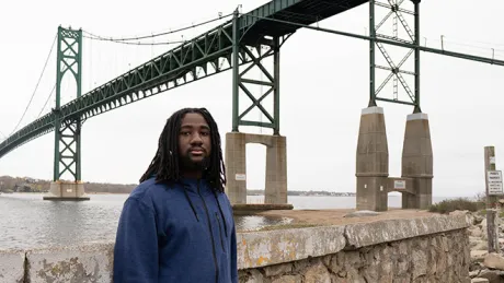 image of RWU senior Christian Thomas on Bristol Campus beneath the Mount Hope Bridge, a popular student hangout