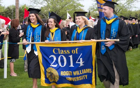 Graduates process with class banner
