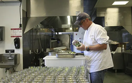A worker finishes packaging a product inside an industrial kitchen.