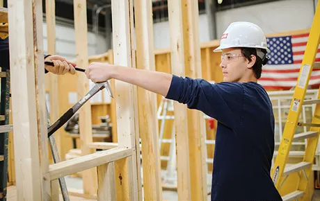 Construction management student at a construction site handing off a tool.