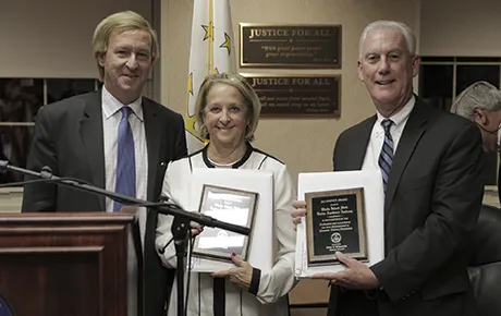 Two men and a woman pose with awards.