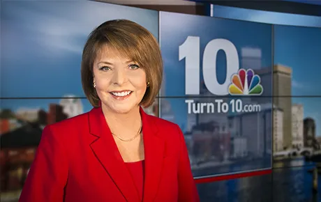 News anchor sitting at the broadcast desk.