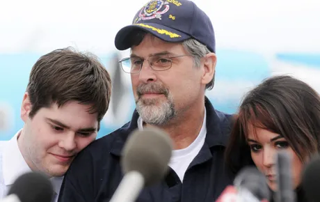 A man is surrounded by family at a press conference.