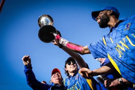 RWU polo team members and coach hold up the championship trophy.