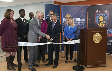 University administrators gather with state and city officials to cut the ribbon on a new campus building.