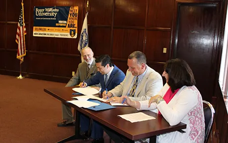 City officials and school administrators sit down to sign an agreement.