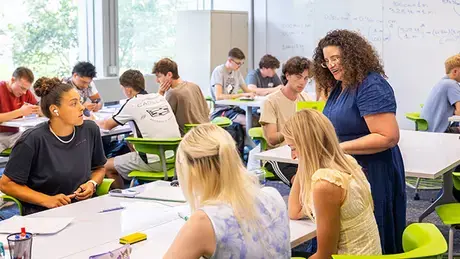 Professor checks on a student's work during class.