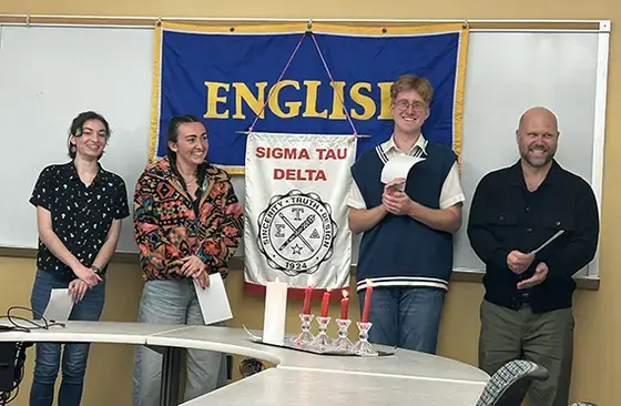 3 Student and one professor standing with flag