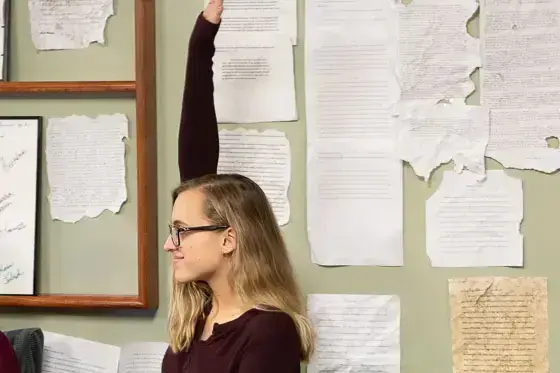 Student raises hand in front of pages of documents
