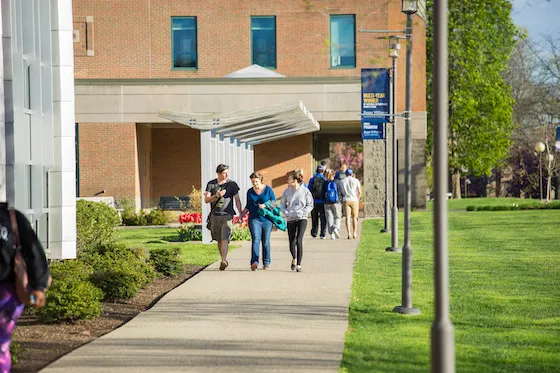 3 students walking together near building on campus