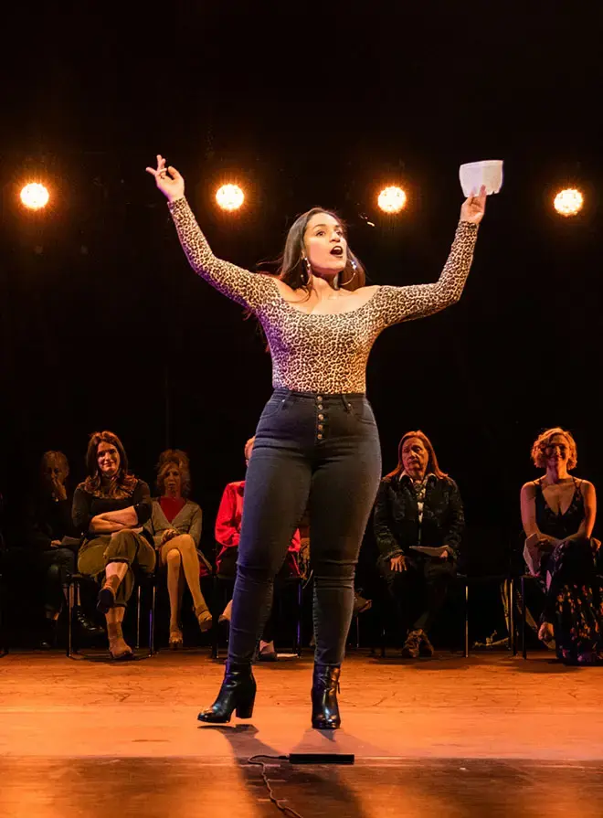 Student stands on stage arms raised