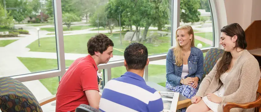 Four current RWU students sitting at a table in a study lounge on campus. 