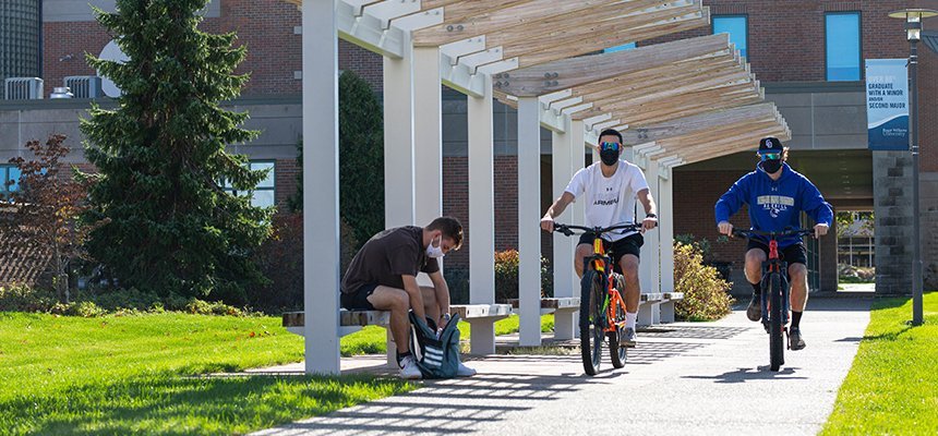 Students in masks ride bikes on campus
