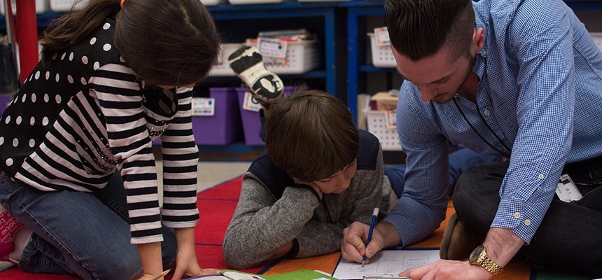 An RWU student helps two elementary schoolers with schoolwork