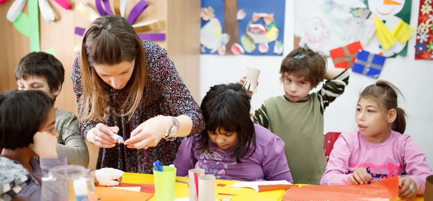 Young students work on craft projects with a female teacher