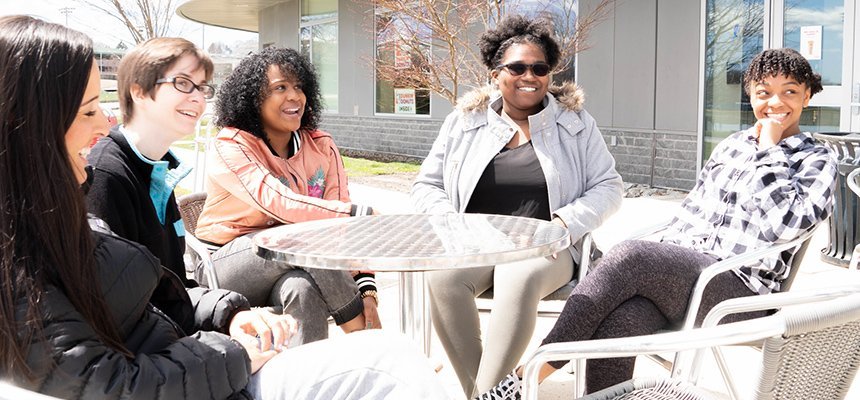 Students sit around a table on the Bristol campus smiling
